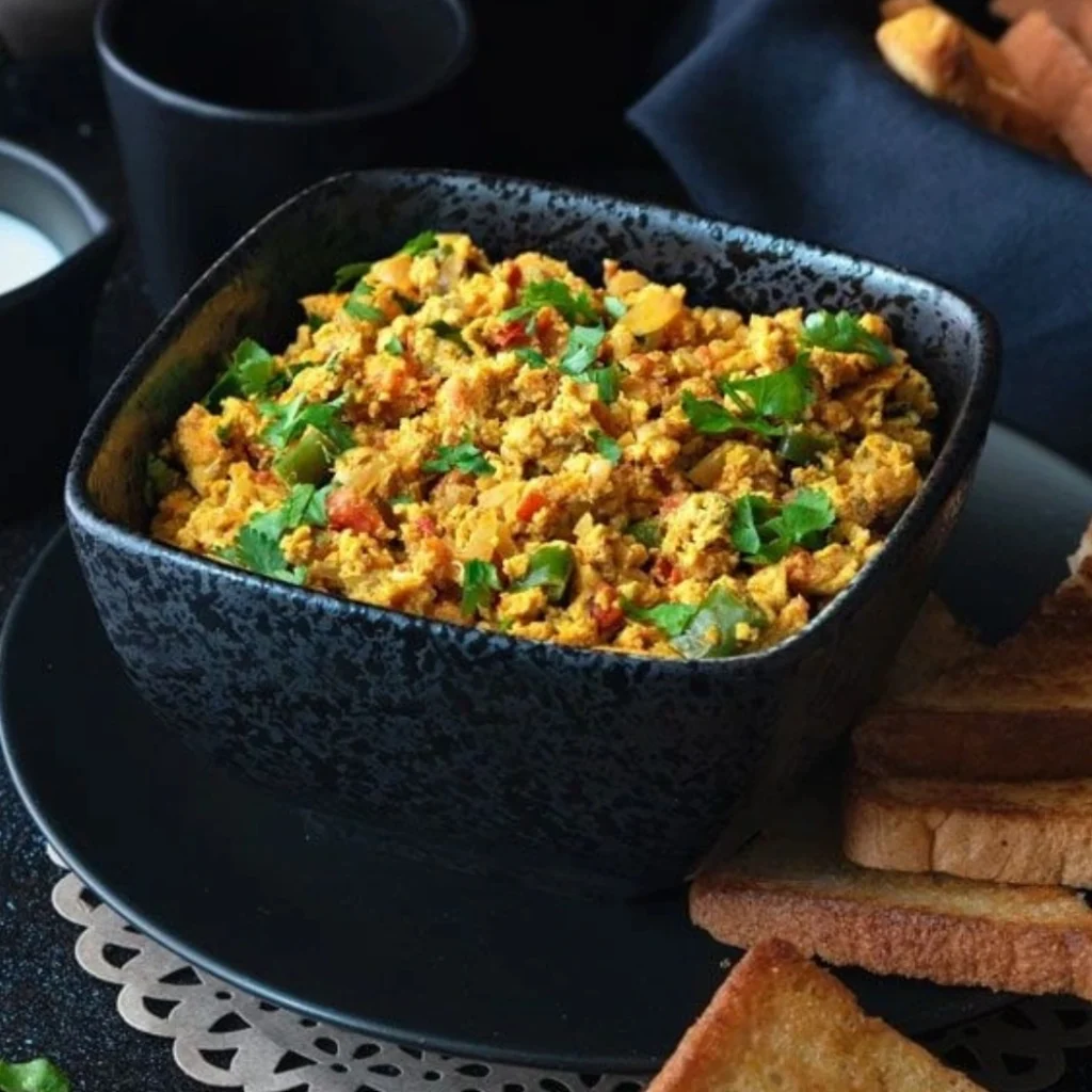 "Spicy Indian egg bhurji served in a black ceramic bowl with toast on the side"