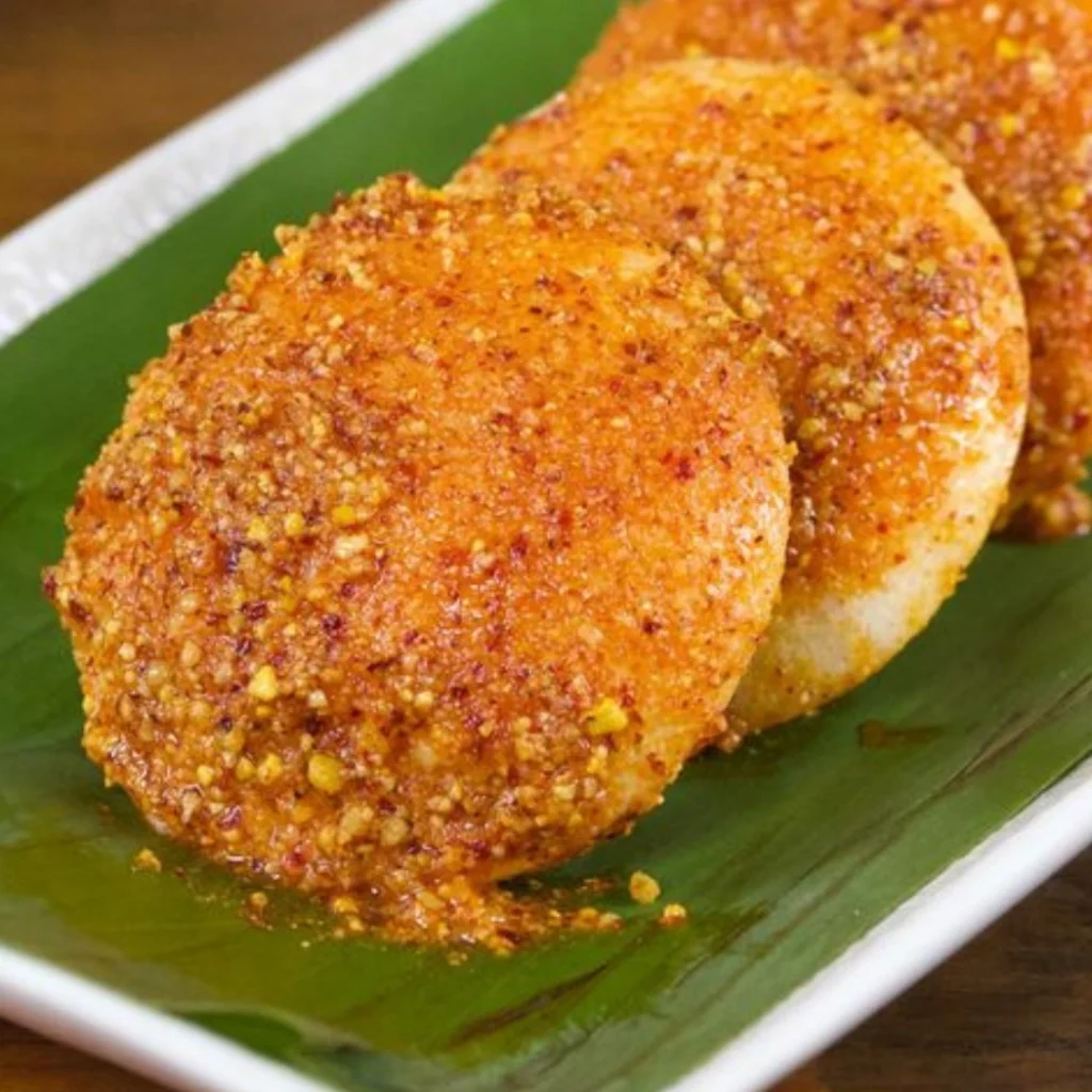 "Golden-brown masala-coated idlis served on fresh banana leaf, featuring a crispy spiced exterior and traditional South Indian presentation"