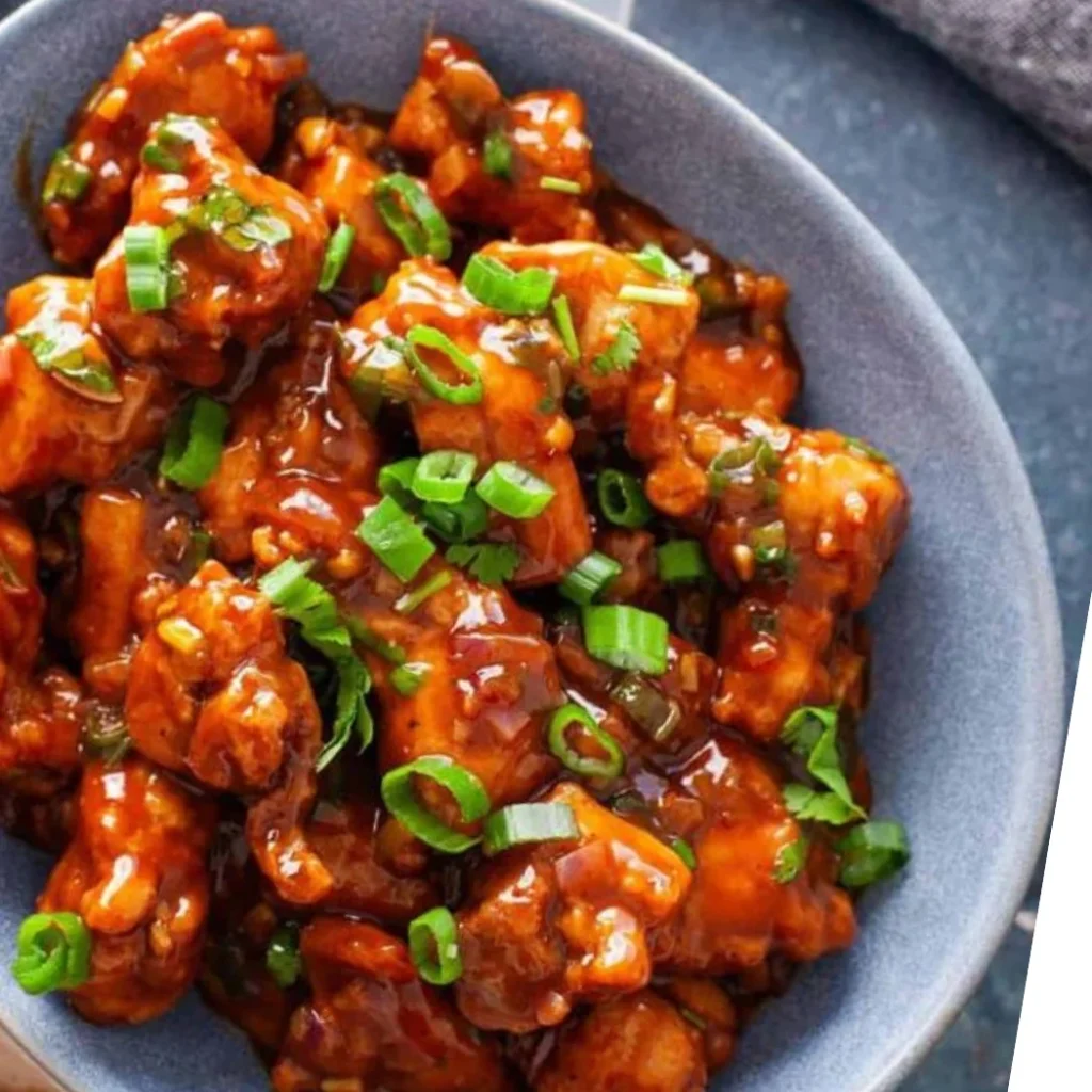 "Spicy orange chicken in a grey bowl garnished with green onions"