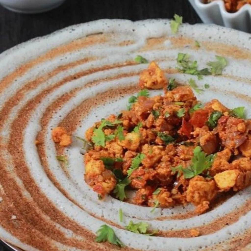 "Spicy paneer bhurji served on a rustic plate with decorative masala swirl and fresh cilantro garnish"