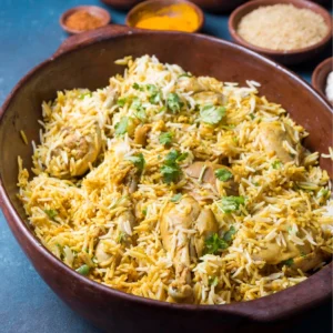 "Homemade chicken biryani served in traditional clay bowl with aromatic basmati rice, tender chicken pieces, and fresh cilantro garnish, accompanied by spice bowls"